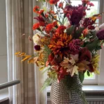 Decoratief bloemstuk in vaas in de kleuren rood, oranje en paars