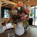 Boeket in opvallende witte vaas in de kleuren oranje, paars en wit