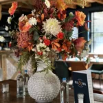 Boeket in opvallende witte vaas in de kleuren oranje, paars en wit