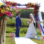 Het bruidspaar onder een kleurrijk bloemenprieel