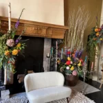 Feestelijke aankleding van een schouw, met kunstzinnige bloemen aan weerszijden