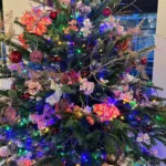 Dichtgeornamenteerde kerstboom voornamelijk in de kleuren paars, wit en oranje