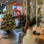Kerstsfeer in een winkel door dichtversierder kerstboom in de kleur zilver met sierlijke witte vaas met witte takken en groene sprieten